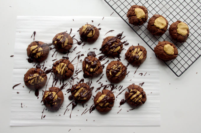 Buckeye Thumbprint Cookies - dense chocolate cookie base topped with a sweet peanut peanut butter ball and drizzled with bittersweet chocolate | www.thebatterthickens.com