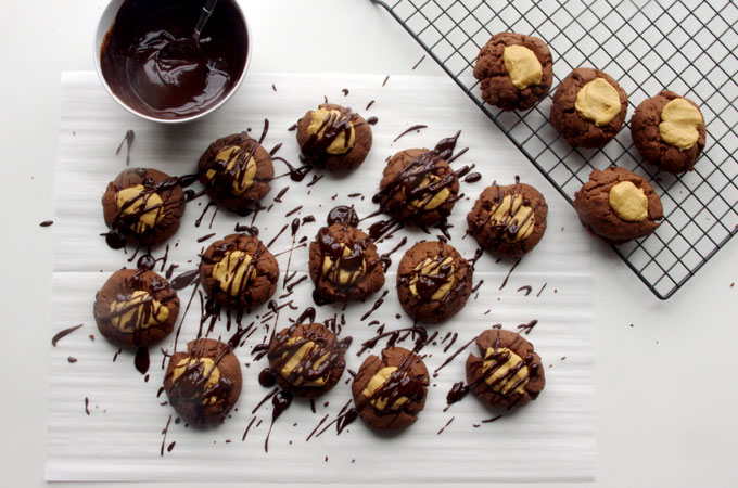 Buckeye Thumbprint Cookies - dense chocolate cookie base topped with a sweet peanut peanut butter ball and drizzled with bittersweet chocolate | www.thebatterthickens.com