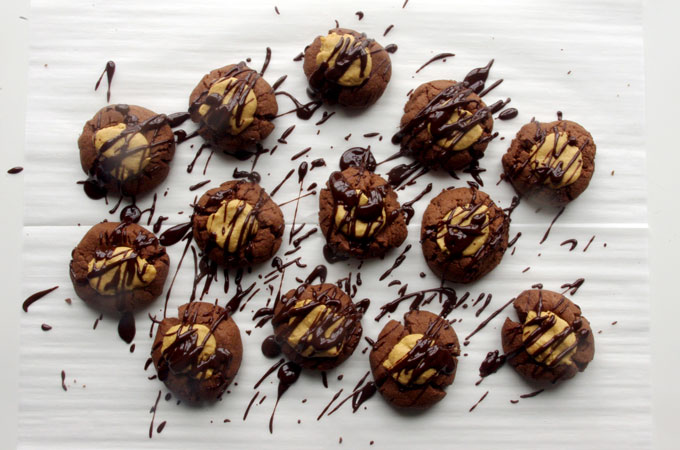 Buckeye Thumbprint Cookies - dense chocolate cookie base topped with a sweet peanut peanut butter ball and drizzled with bittersweet chocolate | www.thebatterthickens.com